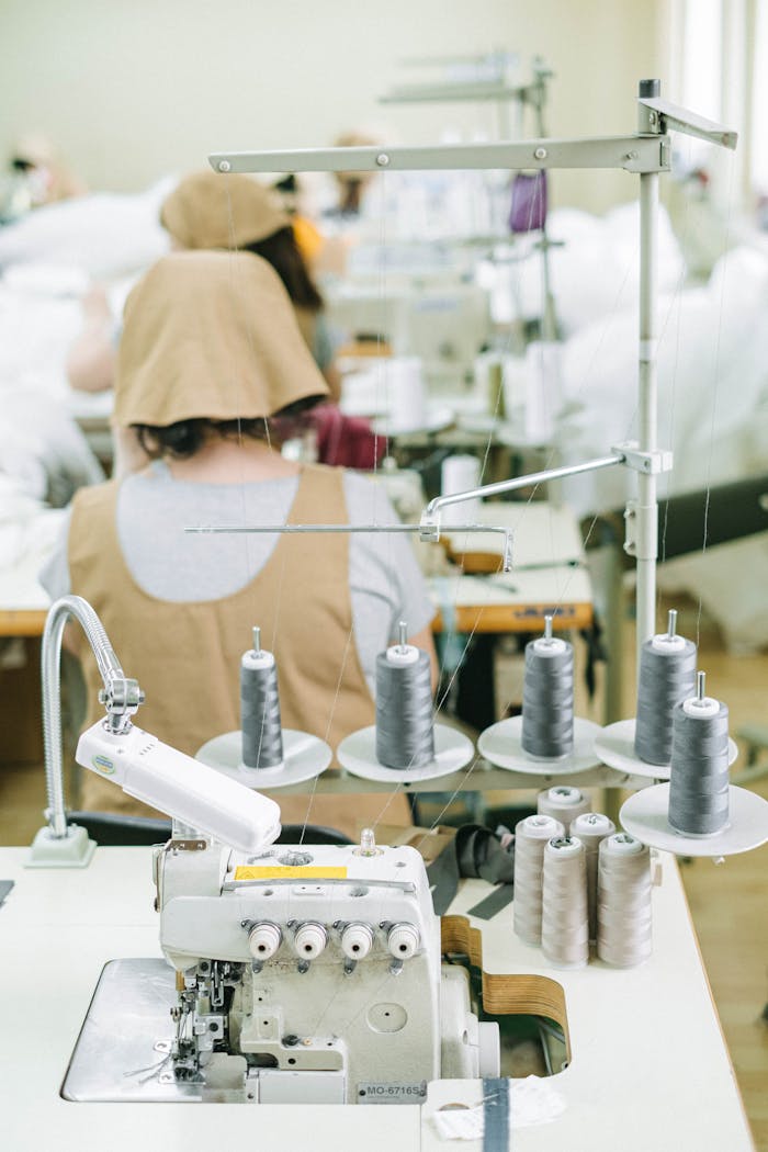 our-experience Sewing machines and workers in a textile factory, highlighting industrial manufacturing processes.