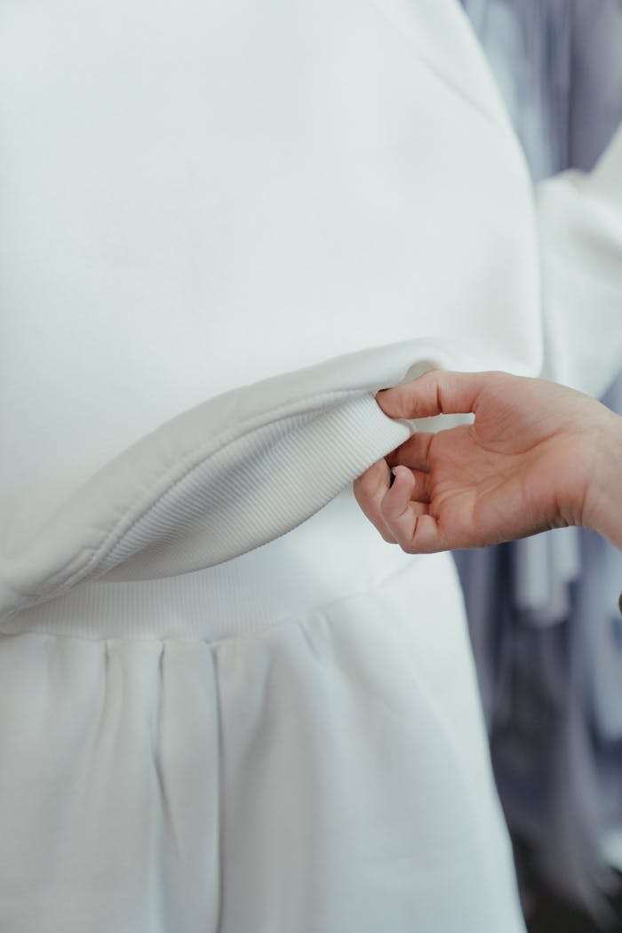 about-img Detailed view of a hand holding white fabric, inspecting quality in a workshop setting.
